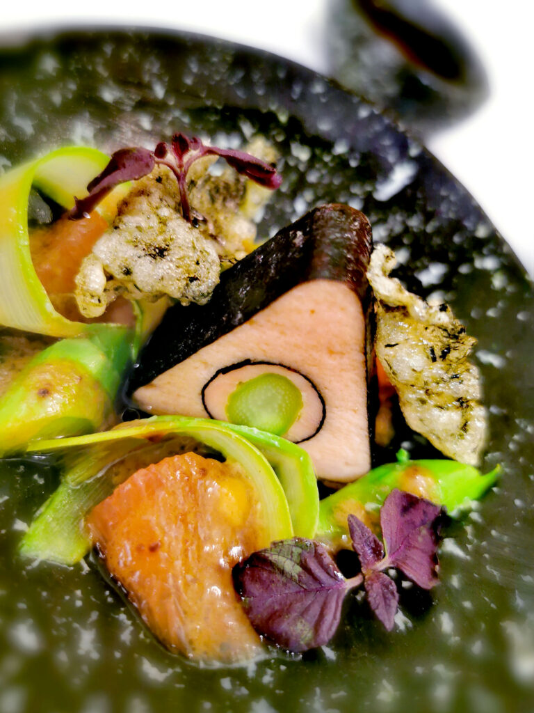 Kreativ angerichtetes Gourmetgericht mit einer dreieckigen Terrine.
