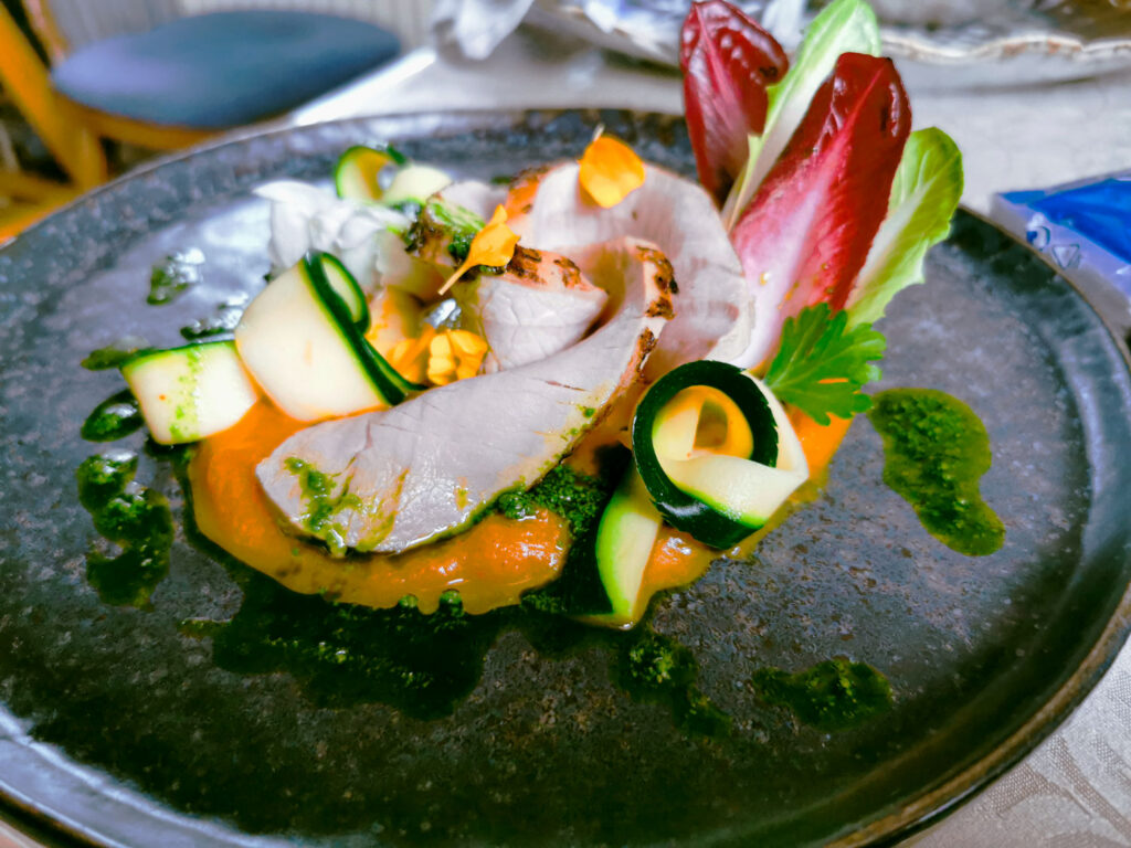 Helles Fleisch auf cremigem Gemüsepüree mit Zucchinibändern, Radicchio und frischen Kräutern