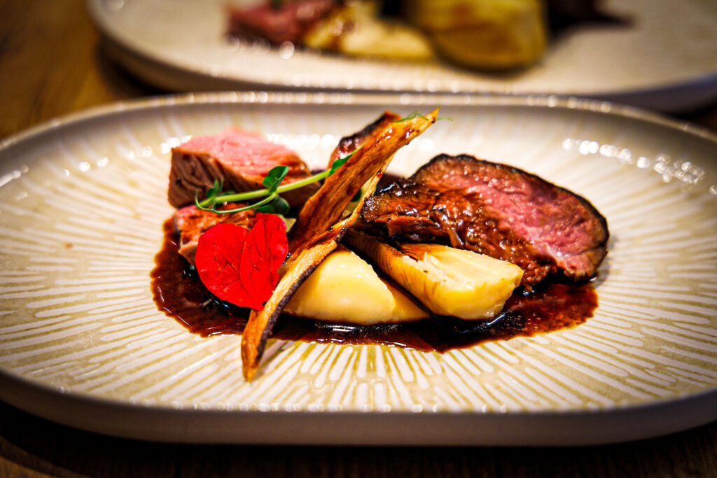 Rosa gebratenes Rinderfilet mit Kartoffelpüree und gebratenem Gemüse auf einem hellen Teller.
